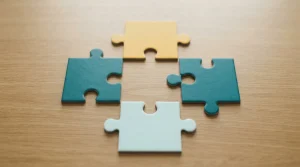 Vier farbige Puzzleteile auf einer hellen Tischplatte